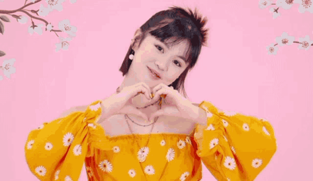 a young girl is making a heart shape with her hands .
