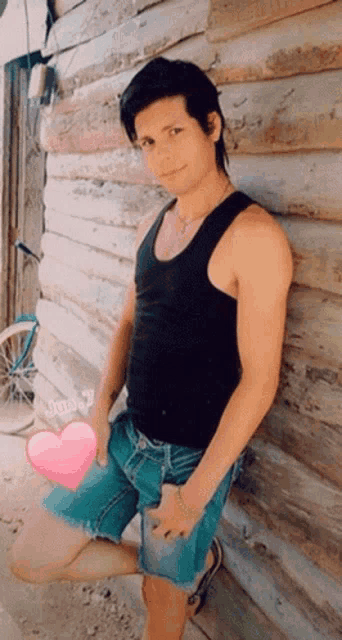 a man leans against a wooden wall with a pink heart in front of him