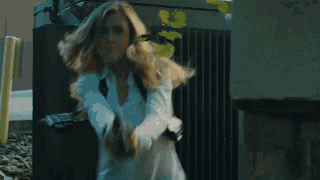a woman is holding a gun with a flame coming out of the barrel