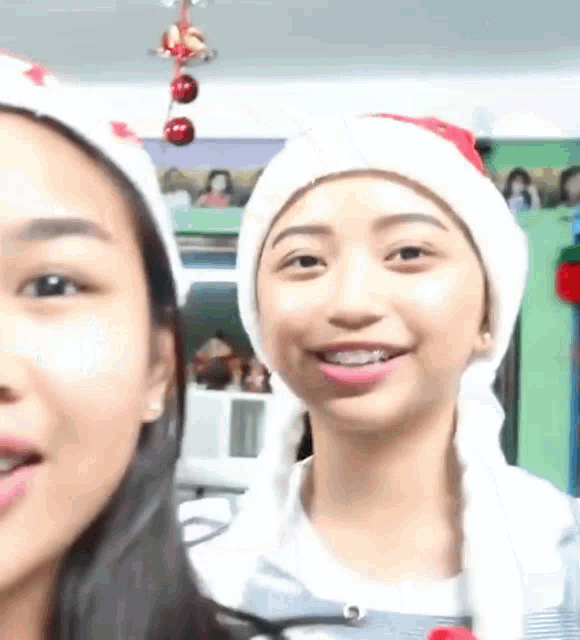 two girls wearing santa hats are smiling for a picture