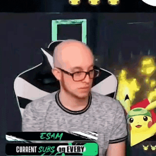 a bald man wearing glasses and a gray shirt is sitting in a chair .