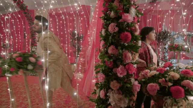 a man and woman are standing in a room with flowers and lights