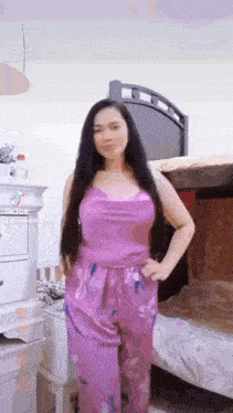 a woman in a purple top and purple pants is standing in front of a bunk bed .