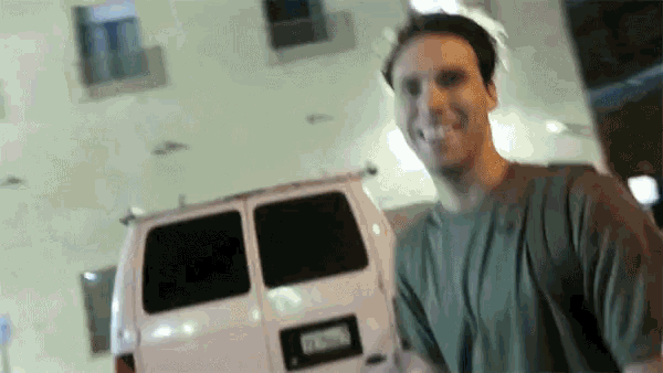 a man smoking a cigarette in front of a white van with a license plate that says ' rc ' on it
