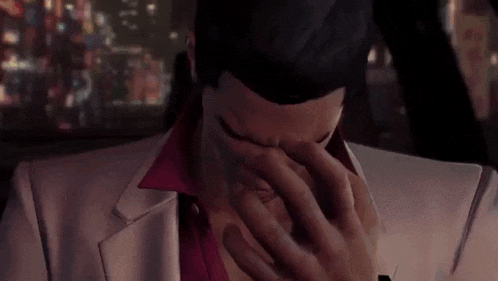 a man in a suit is covering his face with his hand .