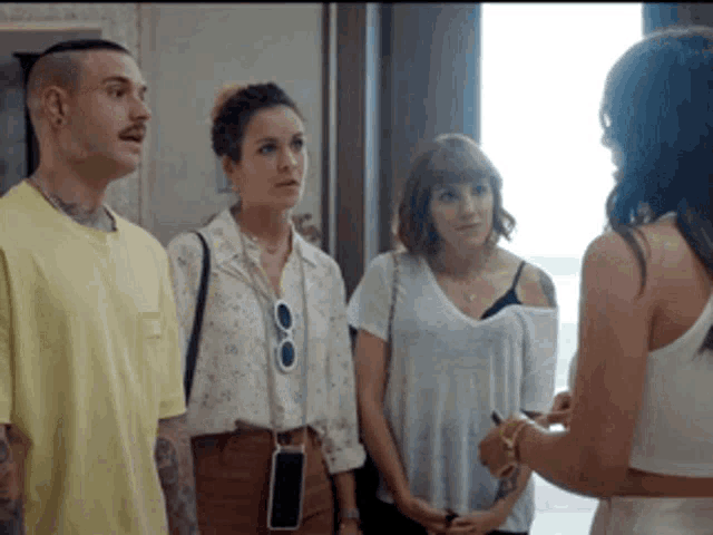 a group of people are standing next to each other talking to a woman