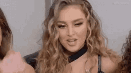 a close up of a woman with curly hair wearing a choker and a bra .