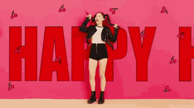 a girl is standing in front of a wall that says happy i