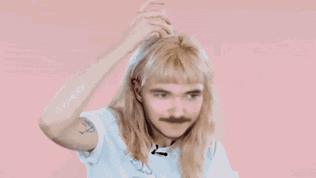 a woman with blonde hair and a mustache is holding her hair up