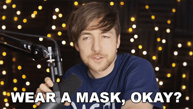 a man in front of a microphone with the words wear a mask okay on the bottom