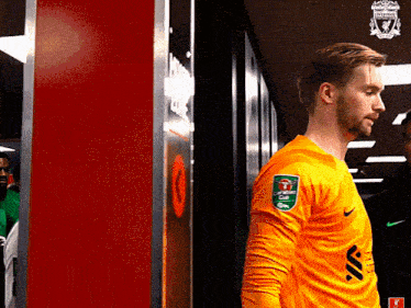 a man in a yellow nike jersey stands in a room