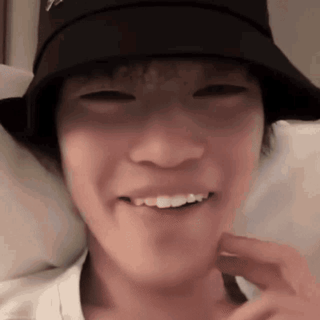 a close up of a person wearing a black bucket hat and smiling .