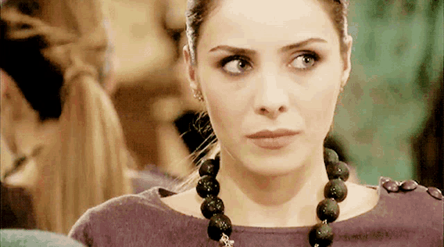 a woman wearing a purple shirt and a necklace with black beads