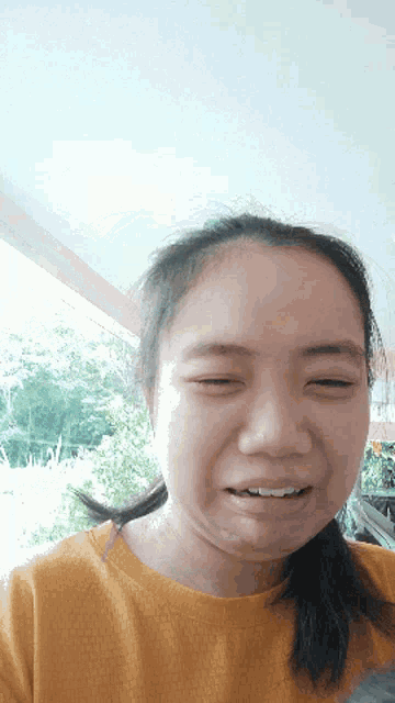 a girl with her eyes closed and a yellow shirt on