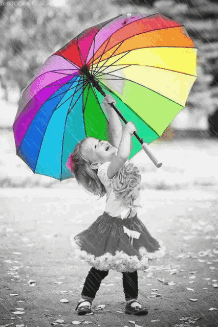 a little girl is holding a colorful umbrella in the rain
