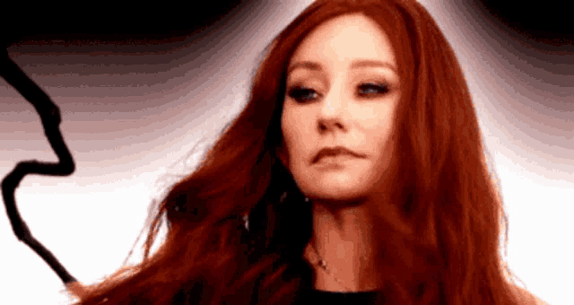 a woman with red hair is holding a whip in her hand