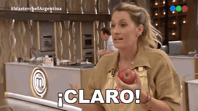 a woman holding an apple in front of a masterchef argentina sign
