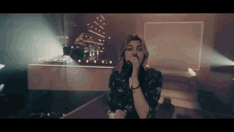 a woman is singing into a microphone on stage in front of a christmas tree .