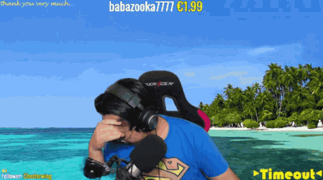 a man wearing headphones and a superman shirt stands in front of a beach