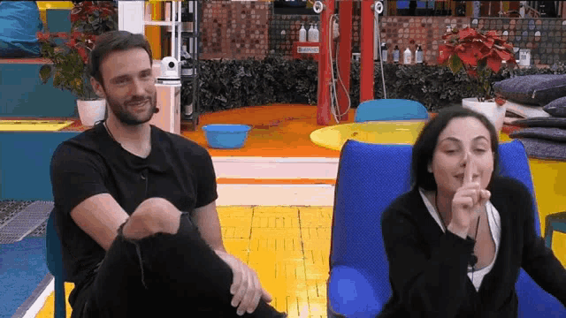a man and a woman are sitting in chairs and the woman is covering her mouth with her hand