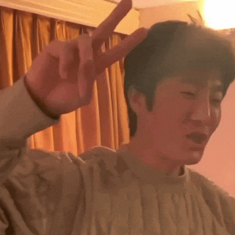 a man in a sweater is making a peace sign with his hand