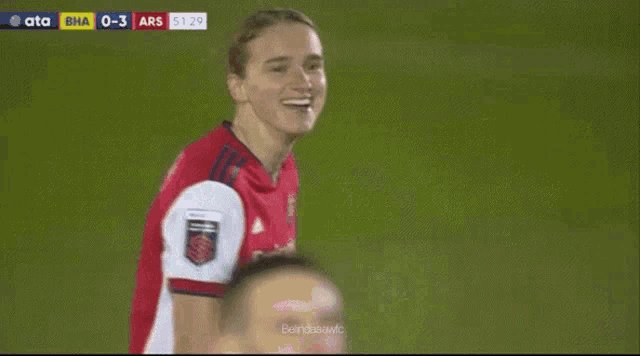 a soccer player wearing a red emirates jersey looks down