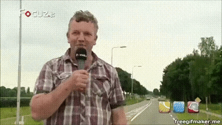 a man in a plaid shirt is holding a microphone and talking into it .