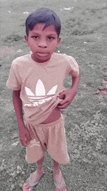 a young boy wearing an adidas t-shirt and shorts