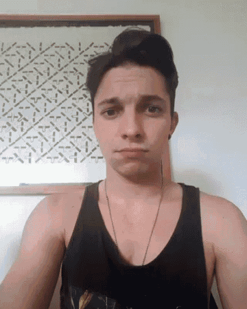 a young man in a black tank top is making a face