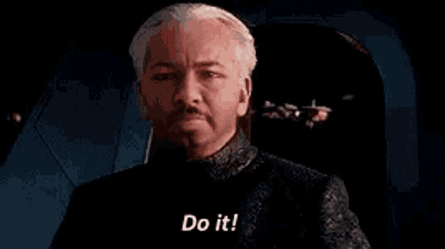 a man with a mustache is sitting in a chair and saying do it .