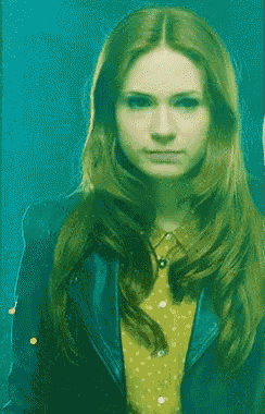 a woman with long red hair wearing a yellow shirt and a blue jacket
