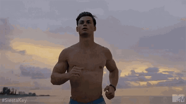 a shirtless man in blue shorts is running on a beach .