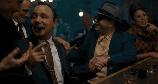 a man in a suit and tie is smoking a cigar while sitting at a bar