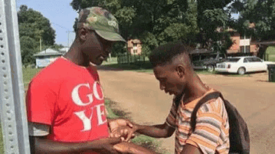 a man in a red shirt is shaking hands with another man in a hat .