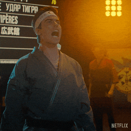 a man in a karate uniform stands in front of a netflix sign