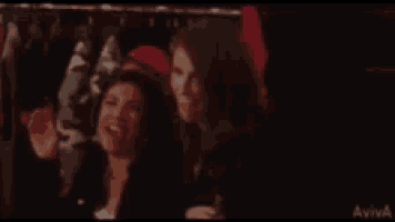 two women wearing santa hats are sitting next to each other and smiling .