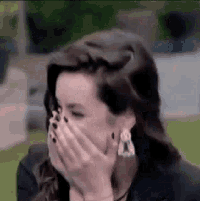 a woman is covering her mouth with her hand .