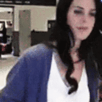 a woman wearing a blue sweater and a white shirt is standing in a room .