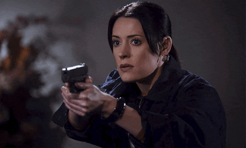 a woman holds a gun in her right hand and looks at it