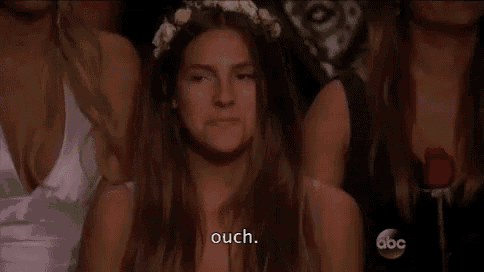 a woman wearing a flower crown is sitting in a crowd of people and talking .