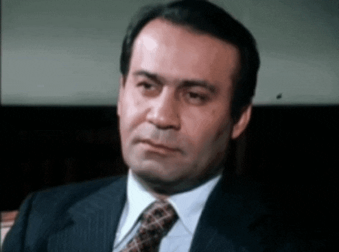 a man in a suit and tie is looking at the camera with a serious look on his face .