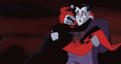 the joker is holding harley quinn in his arms and they are kissing .