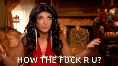 a woman in a red dress is sitting in front of a fireplace and asking how the fuck ru ?