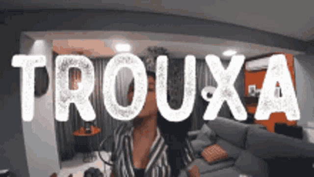 a woman is standing in a living room with the word trouxa on the wall