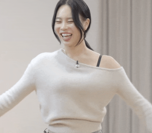 a woman wearing a white off the shoulder sweater is laughing