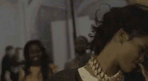 a woman wearing a gold chain necklace is dancing in a room .