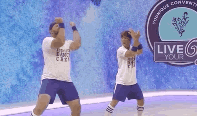 two men dancing in front of a sign that says " live your "