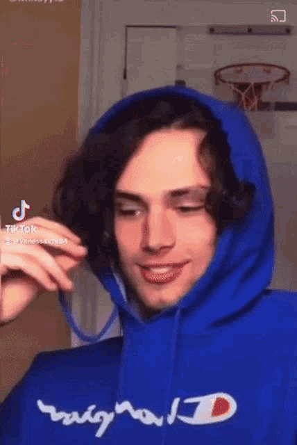 a young man wearing a blue champion hoodie is making a face .