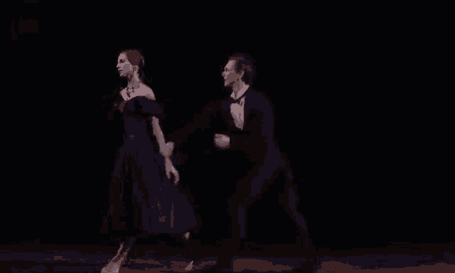 a man and a woman are dancing on a stage in the dark .