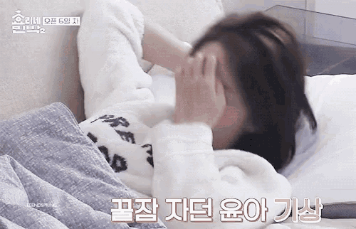 a woman is laying on a bed with her hands on her face .